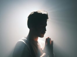 Silhouette of a man in meditative pose with dramatic lighting