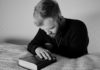Grayscale photo of a bearded man praying